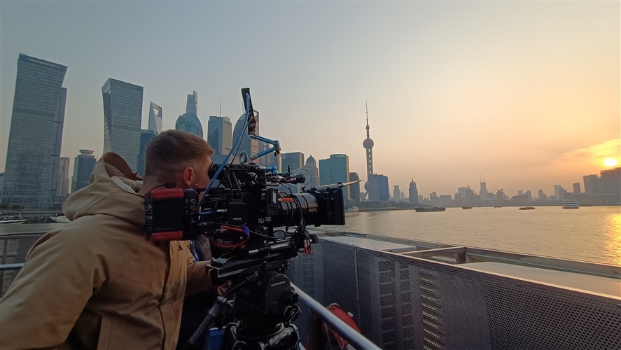 Camera crew filming on the Bund with the Shanghai skyline at sunset