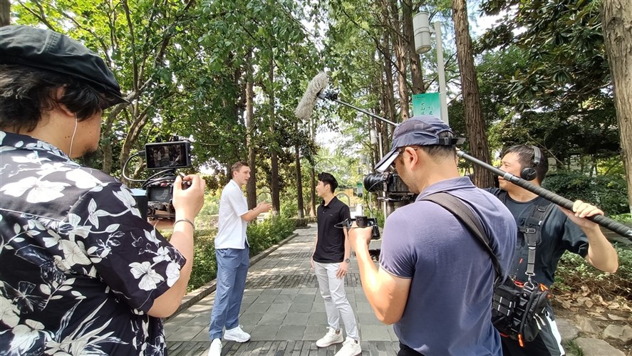 Outdoor interview crew in a Shanghai park with camera and boom support